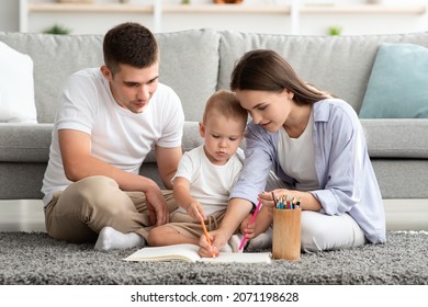 Young Parents With Adorable Infant Baby Drawing Together At Home, Happy Mom And Dad Spending Time With Their Toddler Child, Painting With Pencils While Relaxing On Floor In Living Room, Closeup