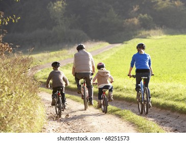 Young parents with children ride bikes in park
