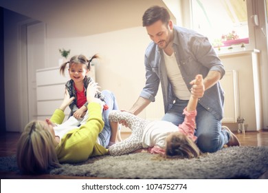 Young parents with daughters playing on floor. - Shutterstock ID 1074752774