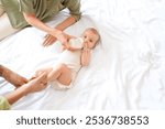 Young parents feeding their little baby with milk from bottle on bed, top view