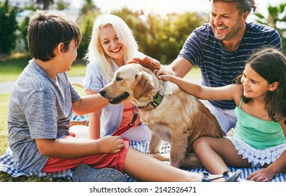 Young parents having fun with children and their pet outdoor at park in summer time - Main focus on dog face - Powered by Shutterstock