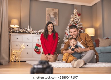 Young parents having fun playing with their toddler boy while spending Christmas day together at home, father teaching son to play with remote controlled toy car - Powered by Shutterstock