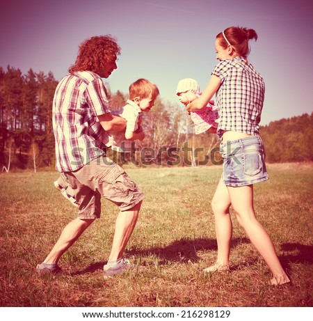 Young parents holding adorable kids playing outdoors- family time