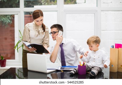 Young Parents With Little Boy Working In Office.Businesman Talking On The Phone