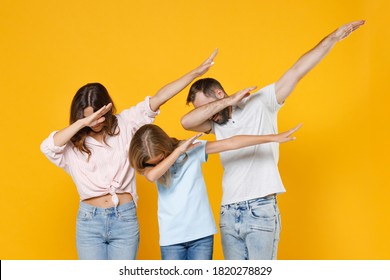 Young Parents Mom Dad With Child Kid Daughter Teen Girl In Basic T-shirts Doing Dab Hip Hop Dance Hands Gesture, Youth Sign Hiding Cover Face Isolated On Yellow Background Studio. Family Day Concept