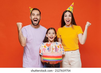 Young parents mom dad with child kid daughter teen girl wear basic t-shirts birthday hat hold cake with candles do winner gesture isolated on yellow background studio. Family day childhood concept. - Powered by Shutterstock