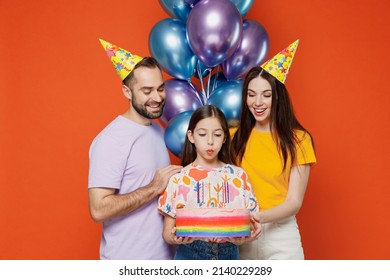 Young parents mom dad with child kid daughter teen girl wear basic t-shirts birthday hat hold cake with candles blow candles making wish isolated on yellow background. Family day childhood concept. - Powered by Shutterstock