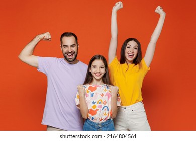 Young Parents Mom Dad With Child Kid Daughter Teen Girl In Basic T-shirts Doing Winner Gesture Celebrate Clenching Fists Say Yes Isolated On Yellow Background Studio. Family Day Parenthood Concept.