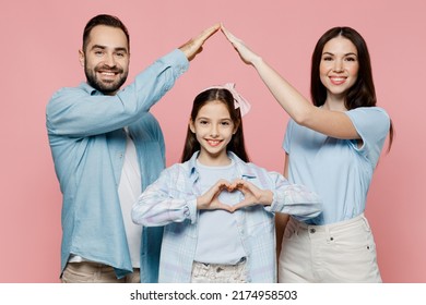 Young Parents Mom Dad With Child Kid Daughter Teen Girl In Blue Clothes Showing Shape Heart Hold Folded Hands Above Head Like House Roof Isolated On Plain Pastel Pink Background. Family Day Concept