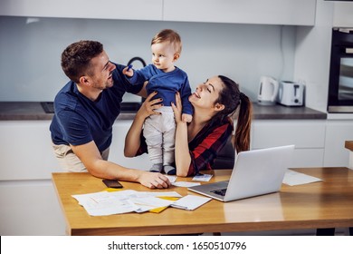 Young Parents Paying Bills Online For Home With Some Help Of Their Beloved Only Son. Home Interior.