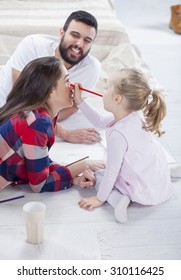 Young Parents Playing With Their Daughter In The Living Room. Family Time