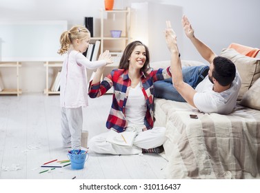 Young Parents Playing With Their Daughter In The Living Room. Family Time