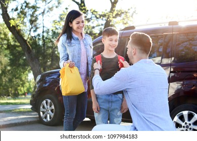 Young Parents Saying Goodbye To Their Little Child Near School