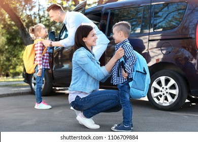 Young Parents Saying Goodbye To Their Little Children Near School