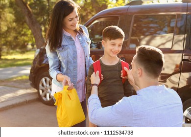 Young Parents Saying Goodbye To Their Little Child Near School