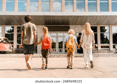 Young parents seeing their kids children to school for lessons classes after summer holidays. Welcome back to school. New academic educational year semester - Powered by Shutterstock