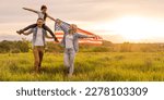 Young parents with their daughter holding American flag in countryside at sunset. Independence Day celebration