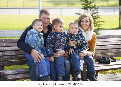 Young Parents And Triplets In The Autumn Park