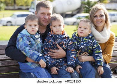 Young Parents And Triplets In The Autumn Park