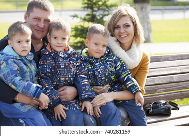 Young Parents And Triplets In The Autumn Park