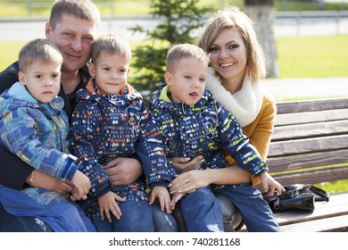 Young Parents And Triplets In The Autumn Park