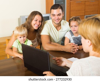 Young Parents And Two Daughters Sitting In Front Of Social Worker