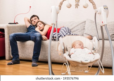 Young Parents Watchin TV While Their Baby Sleeping In His Cradle