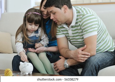 Young Parrent At Home With Beautiful Child Make Savings And Put Coins Money In Piggy Bank