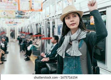 Young Passenger Woman Hand Holding Handle On Train For Safety In Tokyo Japan. Girl Backpacker Looking At  Electronic Marquee Of Arriving Station In Subway. Female Traveler Smiling Waiting To Get Off.