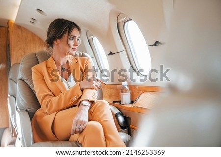 Young passenger woman in yellow clothes is flying in the plane.