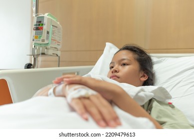 Young Patient Asian Woman Lying On Bed In Hospital With IV Saline Drip To Back Of The Hand, Teenager Sick In Hospital, Selective Focus, Healthcare And Health Insurance Concept.