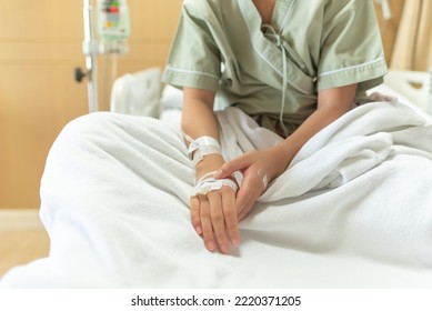 Young Patient Asian Woman Lying On Bed In Hospital With IV Saline Drip To Back Of The Hand, Teenager Sick In Hospital, Selective Focus, Healthcare And Health Insurance Concept.