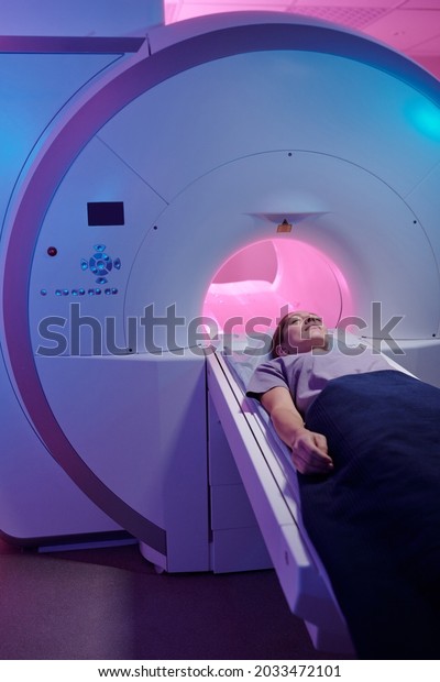Young patient\
covered with blue towel undergoing medical examination in magnetic\
resonance imaging scan\
machine