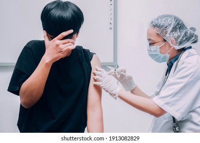 Young patient with fear or scare expression covering his face when being vaccine injected by the doctor