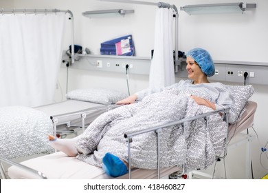 Young Patient Recovering After Surgery In Post Operative Care Room In Modern Hospital. Woman With Cast And Pulse Oximeter After Knee Trauma Operation Monitored In Recovery Room Of Orthopedic Clinic.