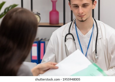 A Young Patient Takes Lab Results Out Of Her Folder. Primary Care Physician. Doctor's Office