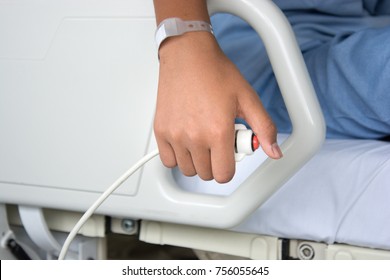 Young patient's hand holding and pressing emergency call button for a nurse from a hygienic hospital bed.