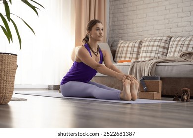 Young and peaceful woman doing Paschimottanasana asana at home. - Powered by Shutterstock