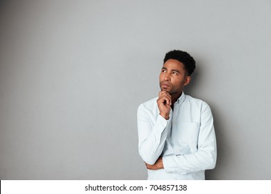 Young pensive african man looking away at copy space isolated over gray background