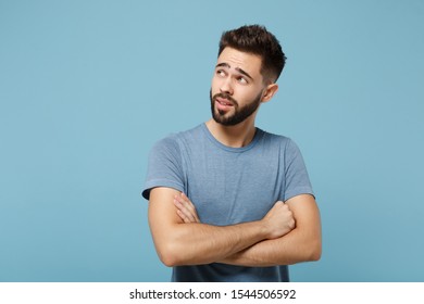 Young pensive handsome man in casual clothes posing isolated on blue background, studio portrait. People sincere emotions lifestyle concept. Mock up copy space. Holding hands crossed, looking aside - Shutterstock ID 1544506592