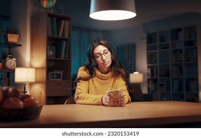 Young pensive woman sitting in the living room at night and drinking coffee - Powered by Shutterstock