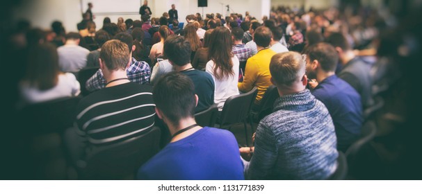 Mucha gente joven en una gran sala escuchando a un orador