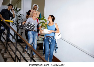 Young People Carrying Card Boxes On Stairways To New Apartment. Roommate Student Friends Moving In College Campus Flat Or Going On Holiday Vacation