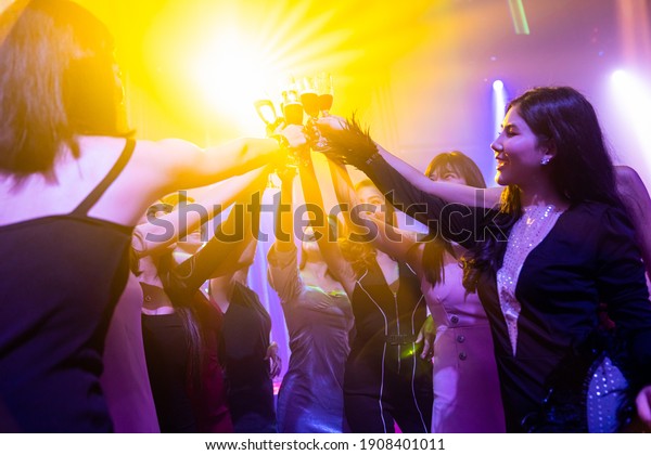 Young people\
celebrating a party, drink and dance . Group of friend toasting\
drinks while having fun at the disco club at night . Friendship and\
nightlife concept .