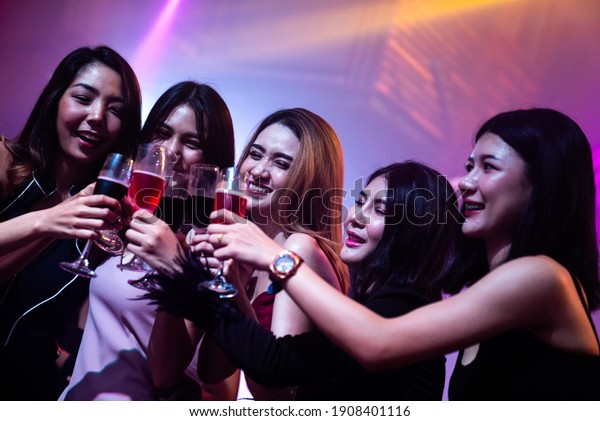 Young people
celebrating a party, drink and dance . Group of friend toasting
drinks while having fun at the disco club at night . Friendship and
nightlife concept .