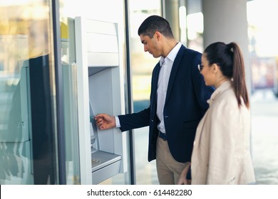 Young People With Credit Card Standing Next To The ATM To Withdraw Money