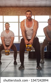 Young People In Crossfit Gym Training With Kettlebells. Small Group Of Male Athletes During Workout. Sports, Fitness, Healthy Lifestyle And Teamwork