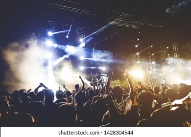 Young people dancing and having fun in summer festival party outdoor - Crowd with hands up celebrating concert event - Soft focus on center hand with yellow background flare - Fun and youth concept