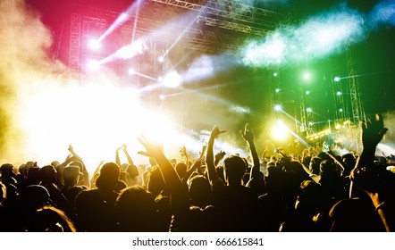 Young people dancing and having fun in summer festival party outdoor - Crowd with hands up celebrating fest concert event - Soft focus on center bottom hand with background flare - Contrast filter