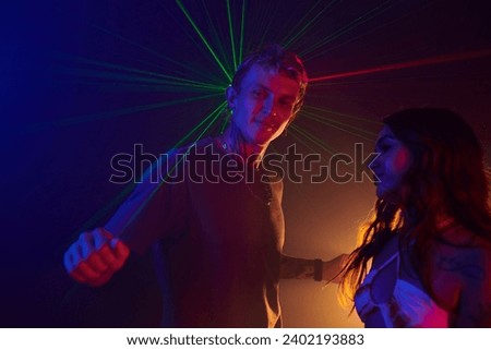 Young people dancing in neon light at rave party